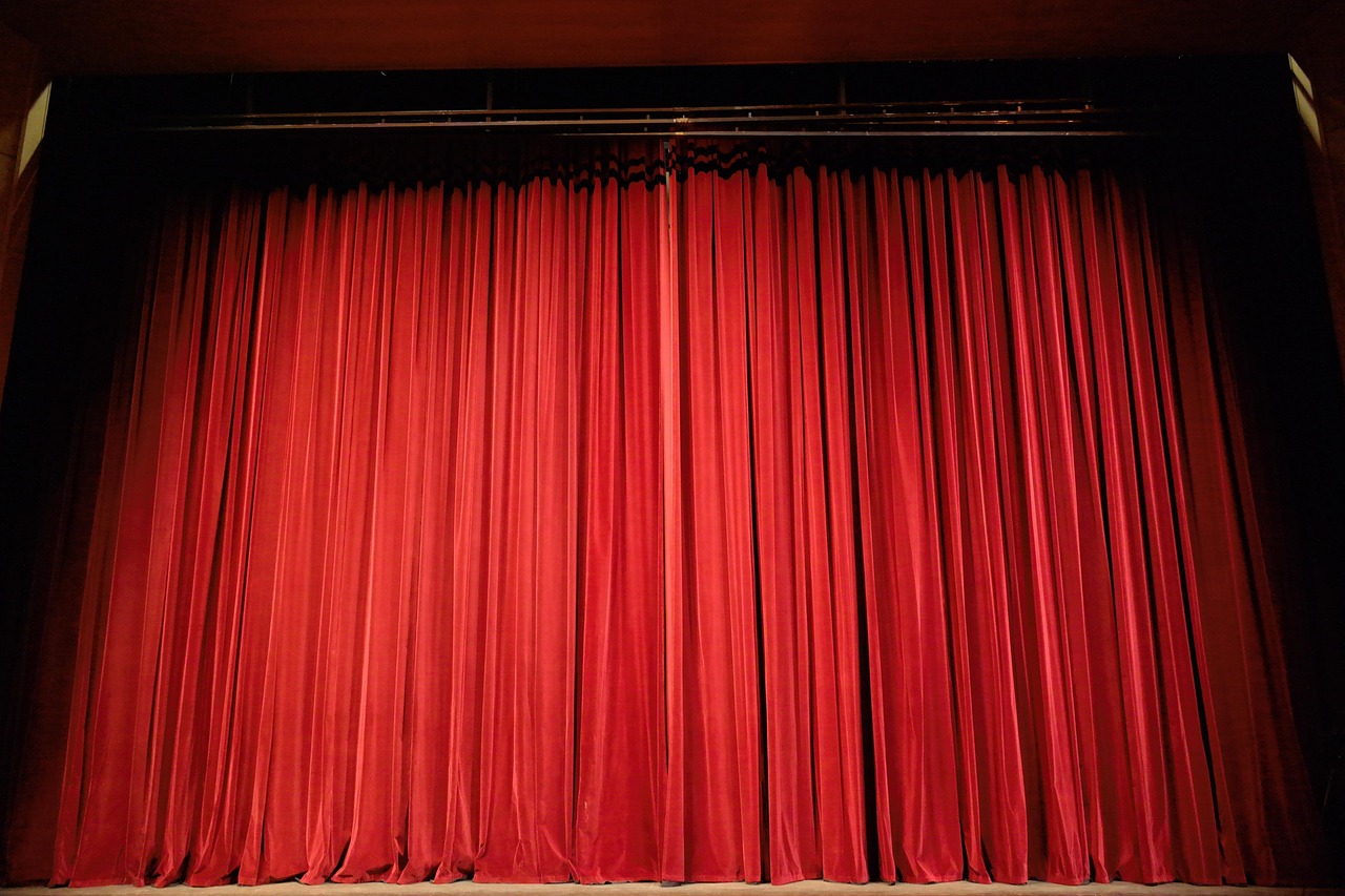 Un rideau de théâtre rouge fermé devant la scène d’une salle de spectacle
